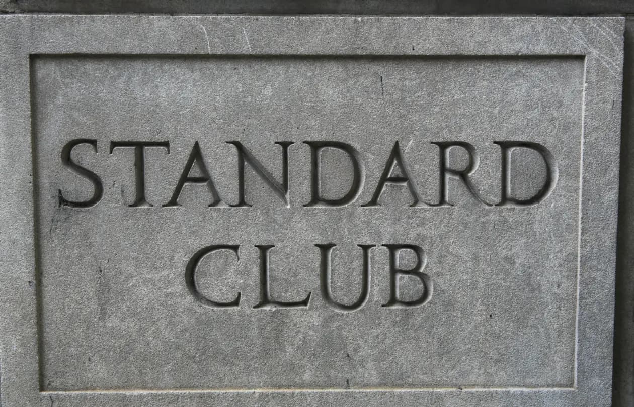 The words Standard Club carved in capital letters into a grey stone panel.