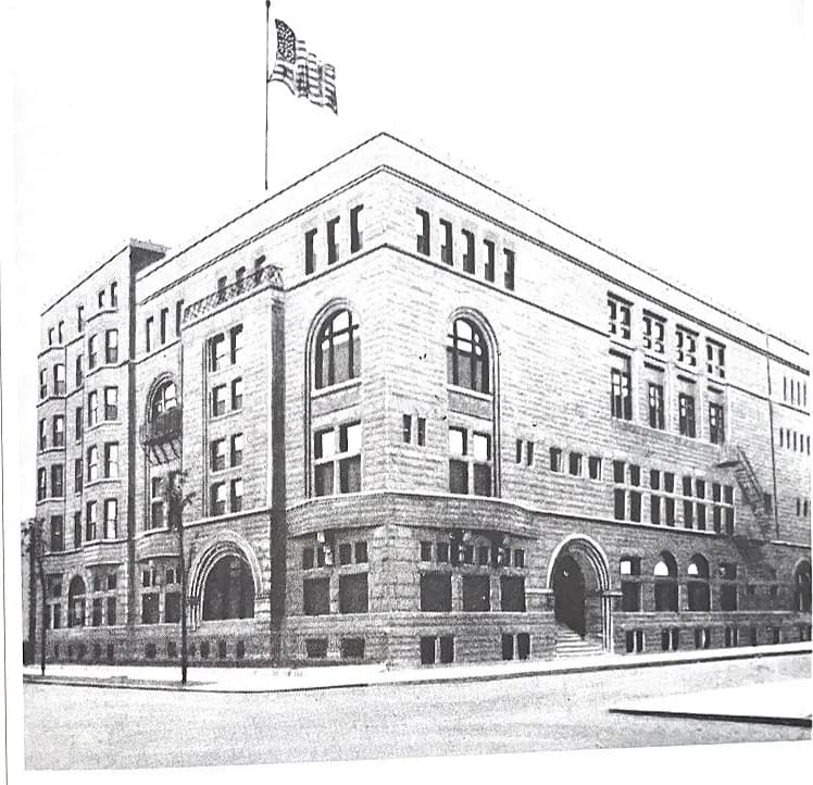 The Standard Club’s second clubhouse at Michigan Avenue and 24th Street, a broad stone building with arched windows and entrances, an American flag flying above the roof.